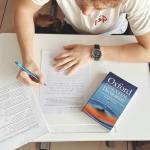 student writing test with oxford dictionary at desk